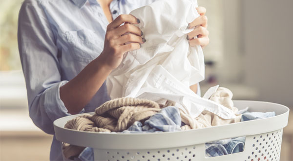 a woman folding clothes into a basket