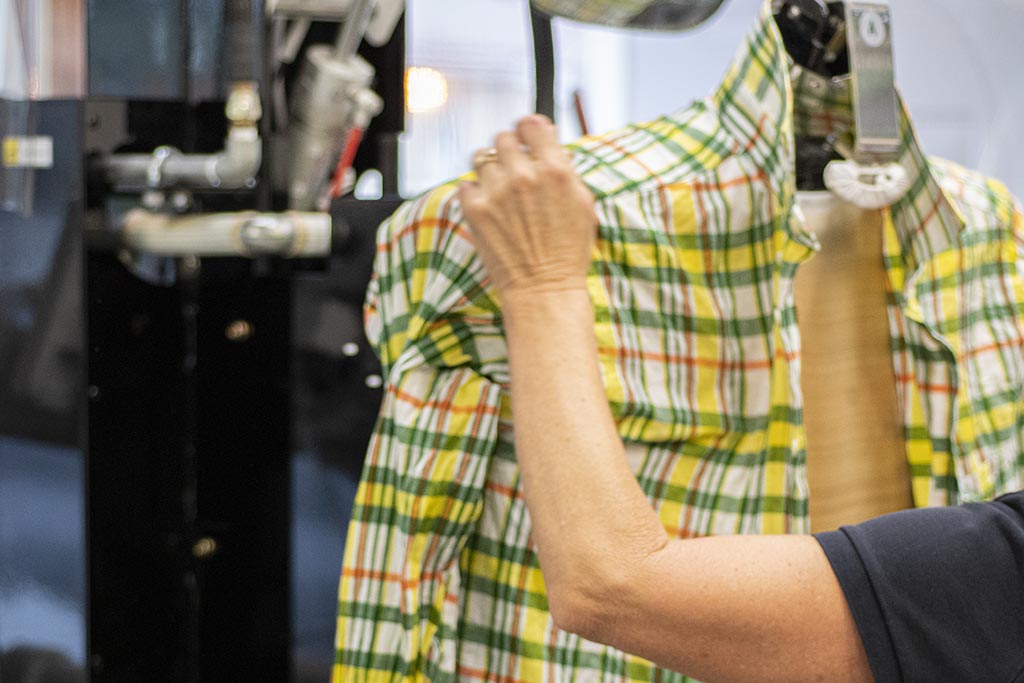a photo of an Urban Valet employee pressing a bottom-up shirt