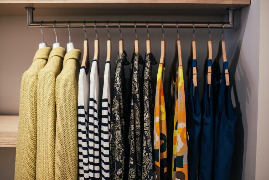Photo of a very organized closet and clothes on hangers.
