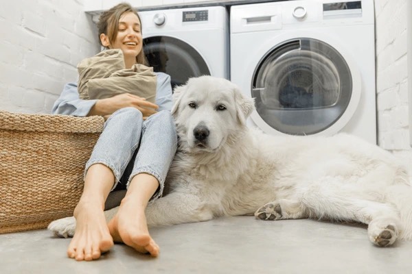 Photo of young female in front of washer & dryer with her dog.