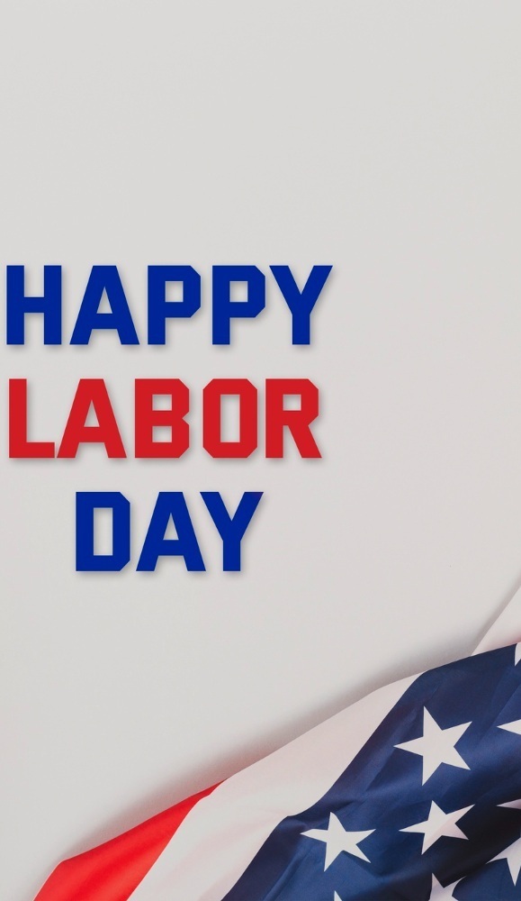 The image features the text "Happy Labor Day" in blue and red letters next to a partial view of an American flag on a light background.