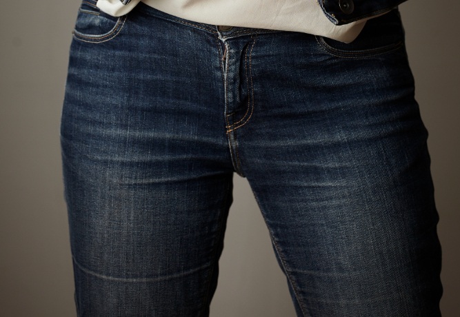 Close-up of a person wearing blue denim jeans and a white shirt.